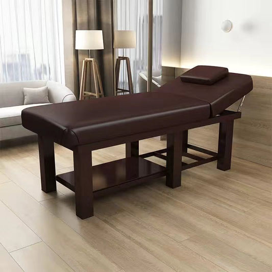A black massage table made of PU leather, displayed in a room setting with two massage cushions.