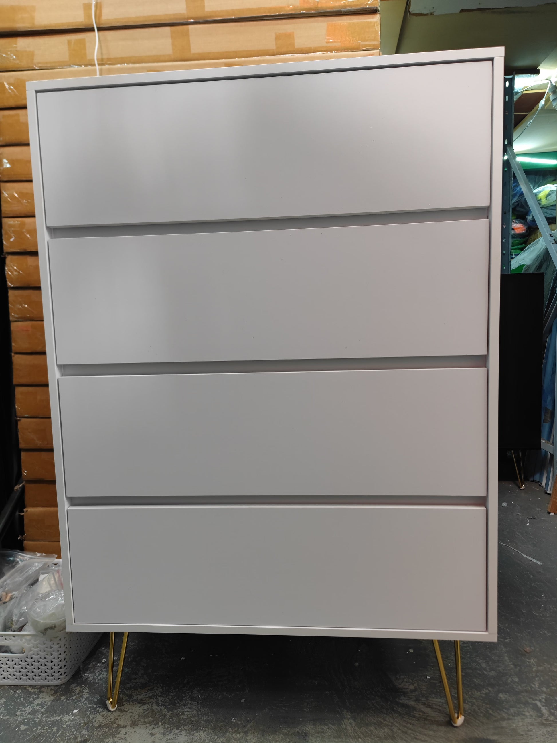 A white tall boy's drawer with multiple drawers, constructed from particle board, seen from the side 